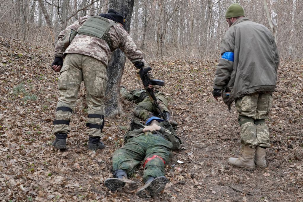 Soldados ucranianos observan los cuerpos de los soldados rusos muertos después de recientes combates. / Foto / AP
