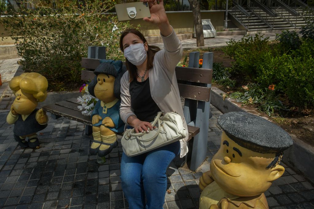 Una mujer se saca una selfie con las esculturas de los personajes creados por Quino en la ciudad de Mendoza.
