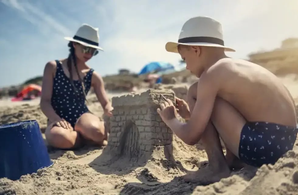 Niños arman castillos de arena en la playa.
