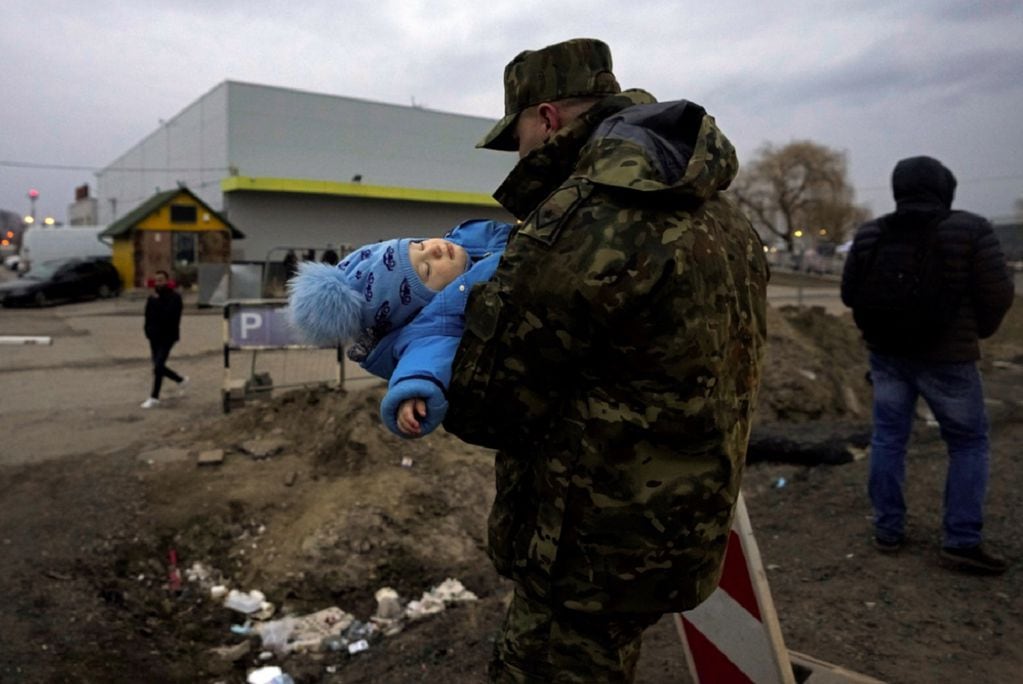 Un soldado polaco lleva al bebé de un refugiado ucraniano a su llegada al cruce fronterizo de Medyka, en el sureste de Polonia. (AP)