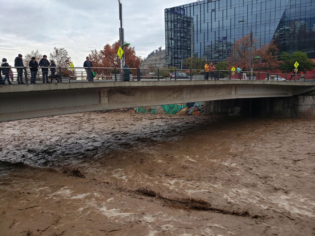 CH0. SANTIAGO (CHILE), 23/06/2023.- Personas observan hoy el elevado caudal del río Mapocho, producto de las intensas lluvias en Santiago (Chile). EFE/ Javier Martín
