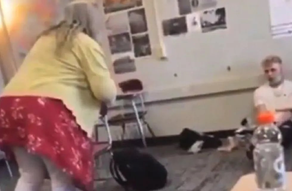 El joven está sentado en el piso de un salón de clases, mientras la maestra lo llama “idiota” e “imbécil”. Foto: Captura de video
