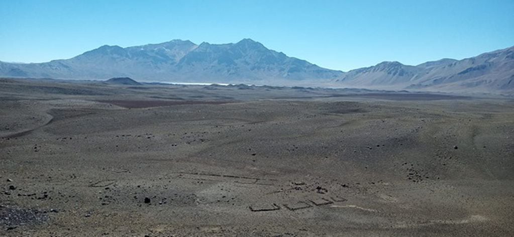 Una vista del sitio denominado LD-S25 que incluye estructuras de muros bajos de roca. Al fondo se puede observar la Laguna de Diamante.
