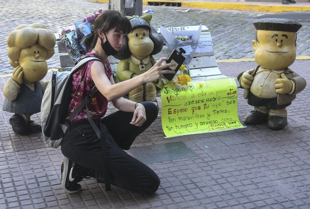Flores y selfies en la escultura de Mafalda sentada en un banco de plaza en el barrio porteño de San Telmo.