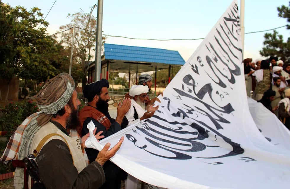 Los combatientes talibanes rezan mientras izan su bandera en la casa del gobernador provincial de Ghazni. (AP)