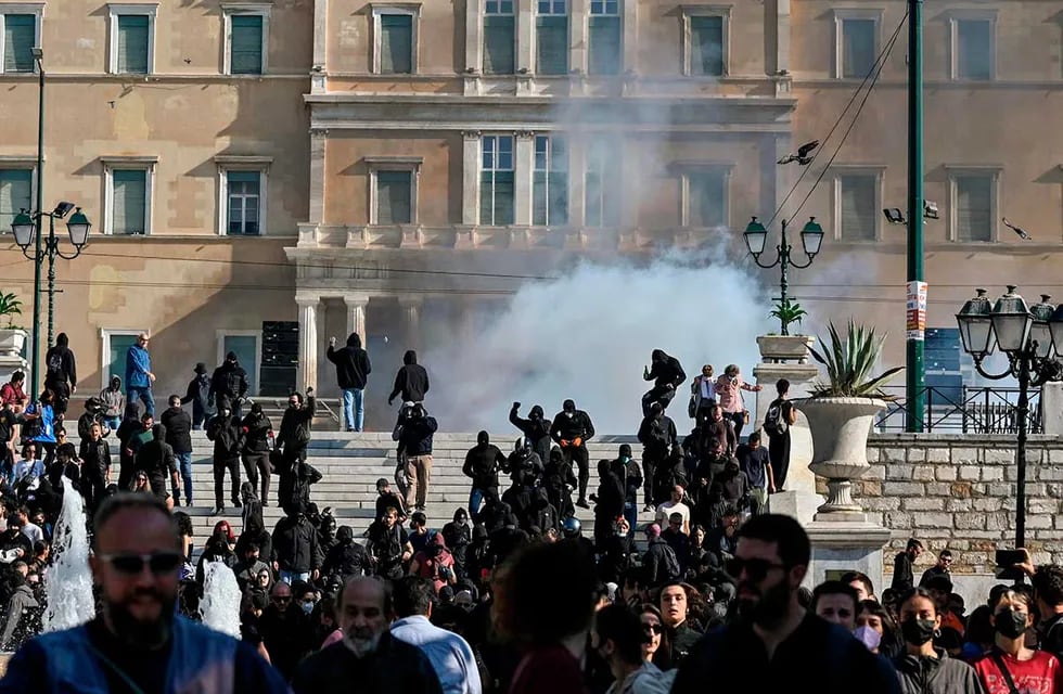 La gente huye de los gases lacrimógenos en el centro de Atenas el 9 de noviembre de 2022 después de que un grupo de jóvenes arrojara cócteles molotov durante las protestas.