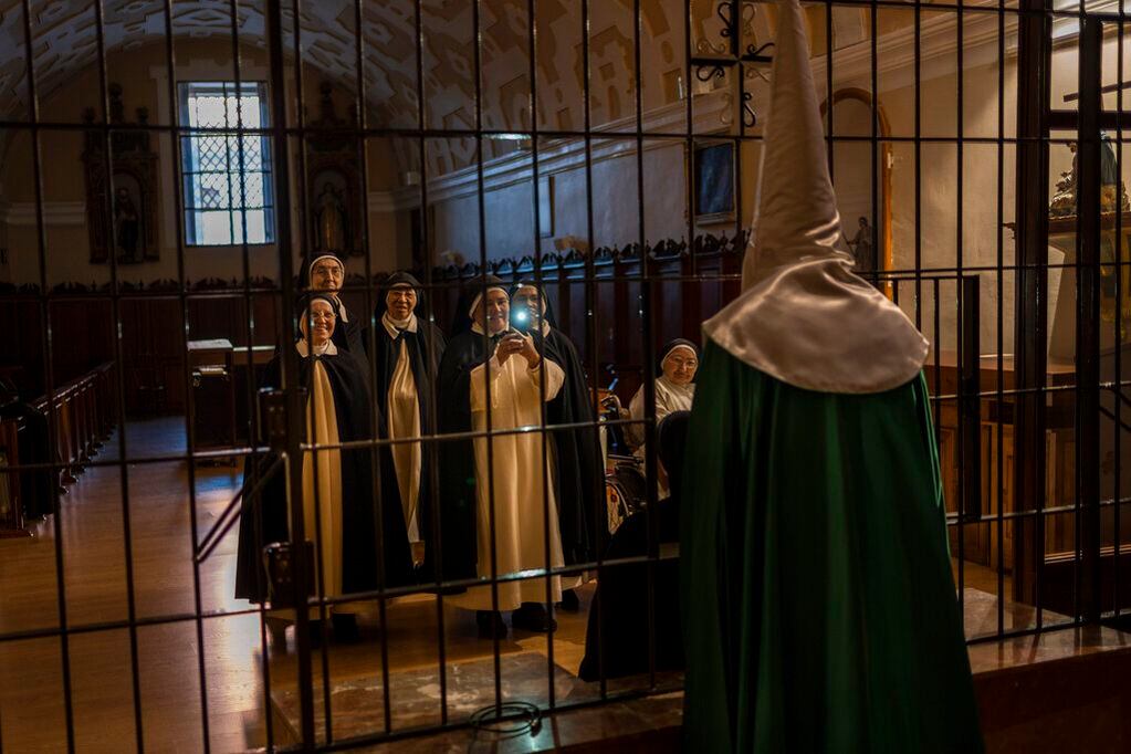 Monjas toman una fotografía a un penitente de la cofradía de la Virgen de la Esperanza, en Zamora, España, el 14 de abril de 2022. (AP Foto/Bernat Armangué)