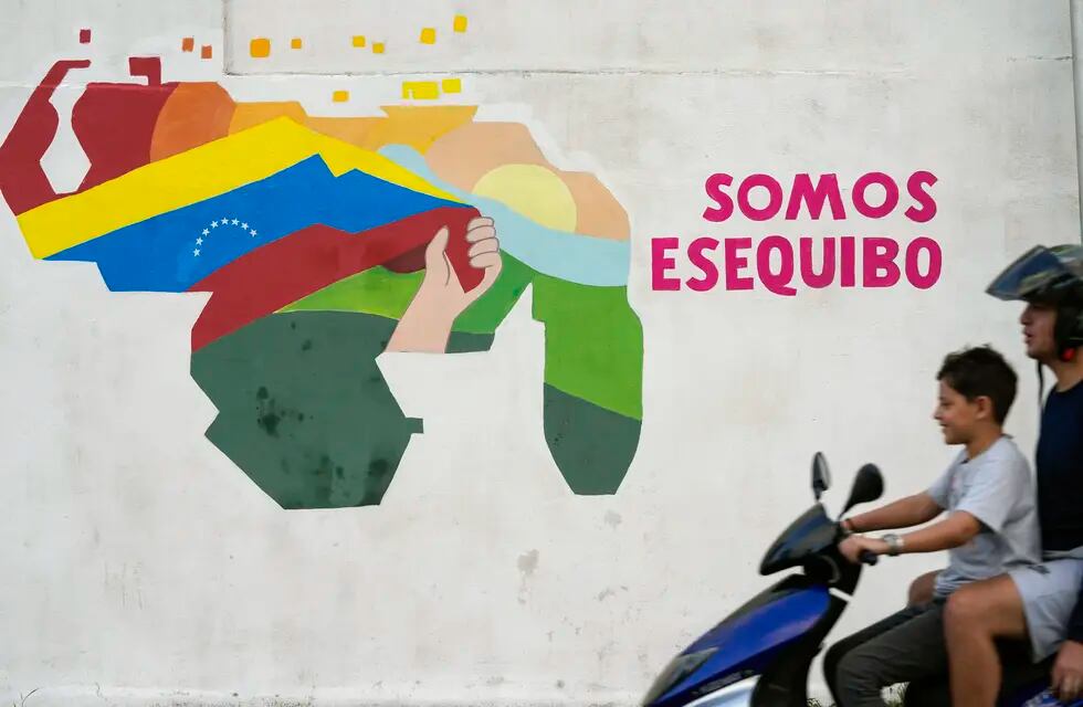 Un niño conduce una motocicleta por delante de un mural con el mapa de Venezuela, que incluye el territorio de Esequibo, en el vecindario 23 de Enero de Caracas, Venezuela, el 11 de diciembre de 2023. (AP Foto/Matías Delacroix)