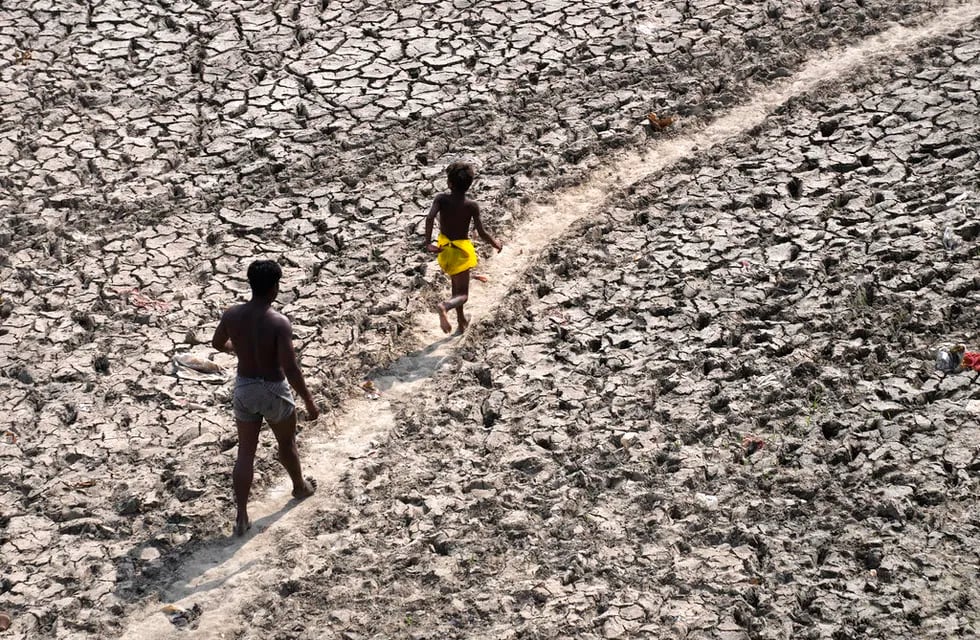 Un hombre y un niño caminan a través del lecho casi seco del río Yamuna luego de una ola de calor en 2022. / Archivo / AP