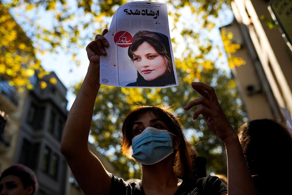 Una mujer sostiene una copia de un artículo de periódico con la foto del iraní Mahsa Amini. Foto: Gentileza