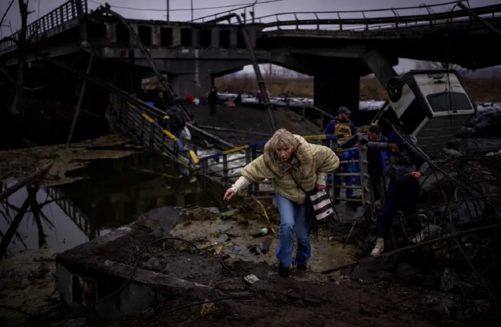 Una mujer corre mientras huye con su familia a través de un puente destruido en las afueras de Kiev, Ucrania. (AP)