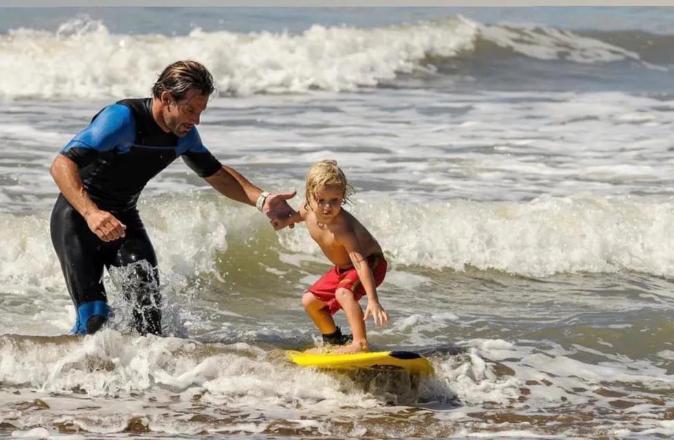 Martín enseñando a surfear a Thiago hace 12 años. / Gentileza.