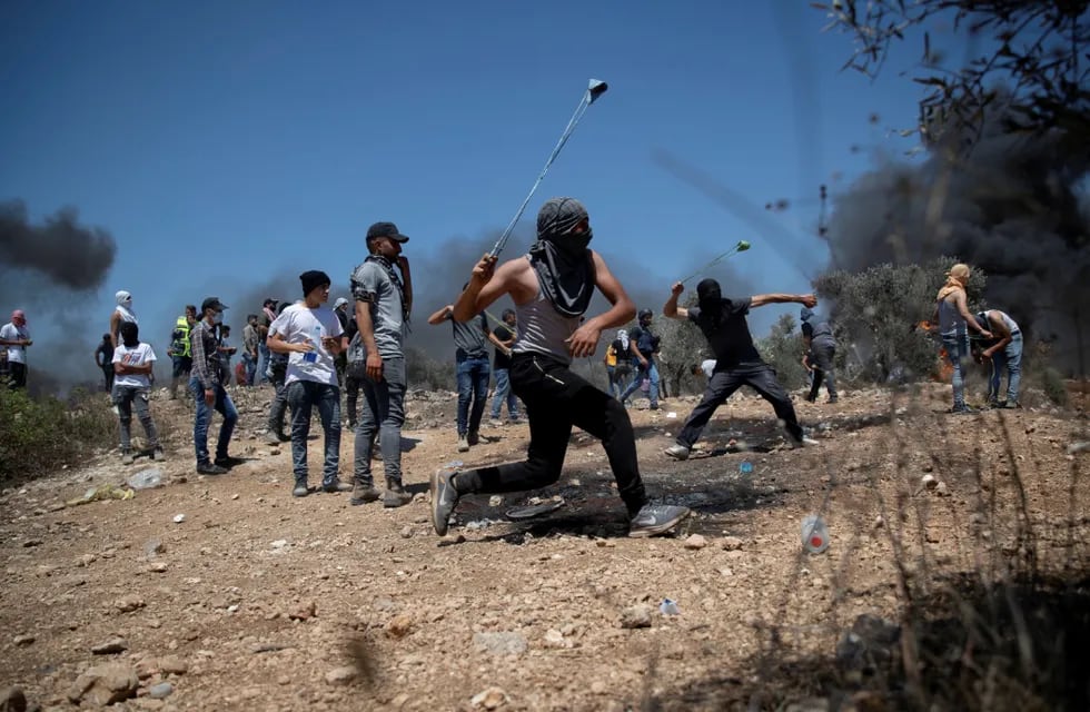 Manifestantes palestinos utilizan una honda para lanzar piedras contra las fuerzas de seguridad israelíes en Cisjordania. (AP)