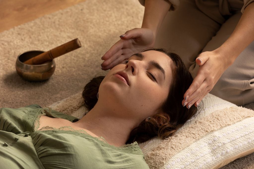 Profile view of a cute young woman getting her energy balanced at a reiki session in a health clinic and spa