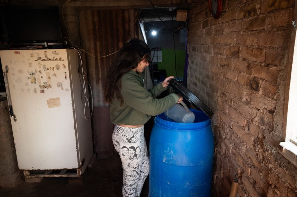 Solange Sallustro sacando agua de un bidón para cocinar. | Foto: Ignacio Blanco / Los Andes 