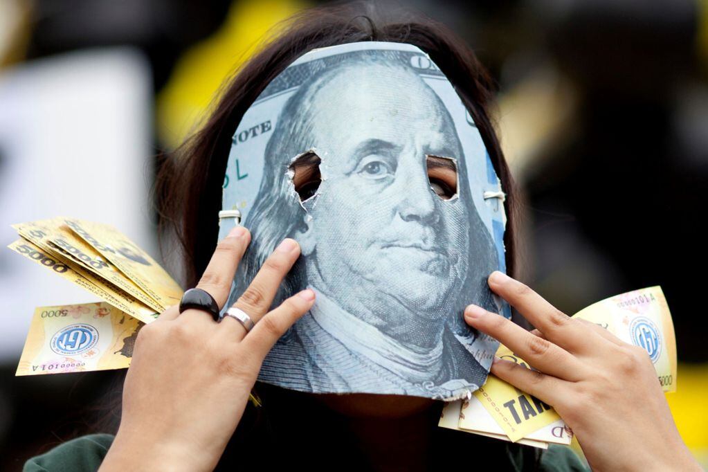 Una persona enmascarada con un detalle de un billete de 100 dólares, en protesta contra el acuerdo que firmó el gobierno de Mauricio Macri con el FMI.
