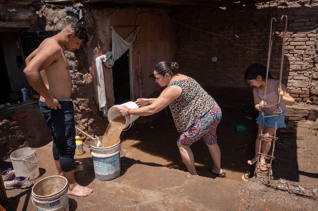 Carmen Fernández y sus hijos intentaban sacar, ayer a la mañana, el agua que se metió a su casa el jueves.