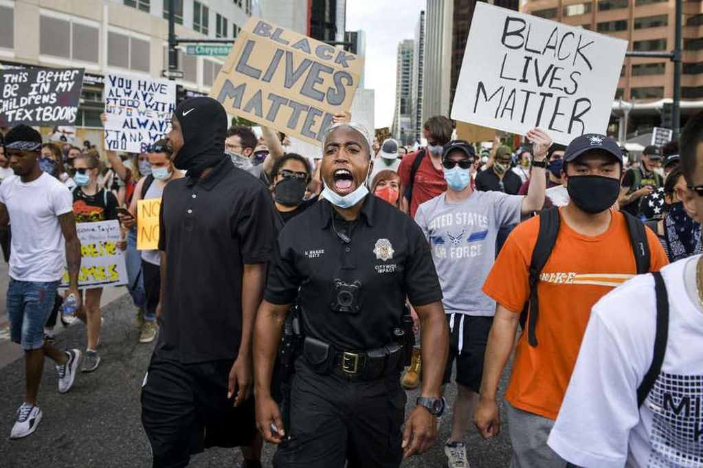 
AFP | El oficial de policía de Denver Nate Magee canta con los manifestantes durante el quinto día de manifestaciones en Denver, Colorado.
   