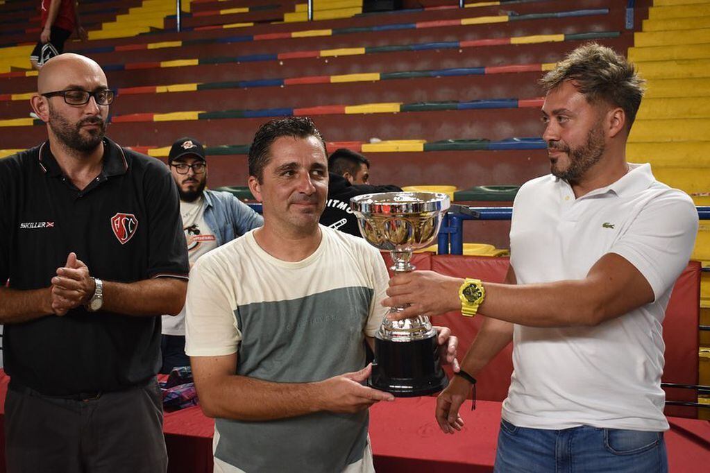 El presidente de Atenas Sport Club, Nahuel García, recibe la copa en manos del presidente de la FBPM, Nicolás Popón. / Gentileza: FBPM.