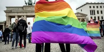  Dos personas identificadas con la nueva unión homosexual festejan en Berlín cubiertos con una bandera arcoiris.