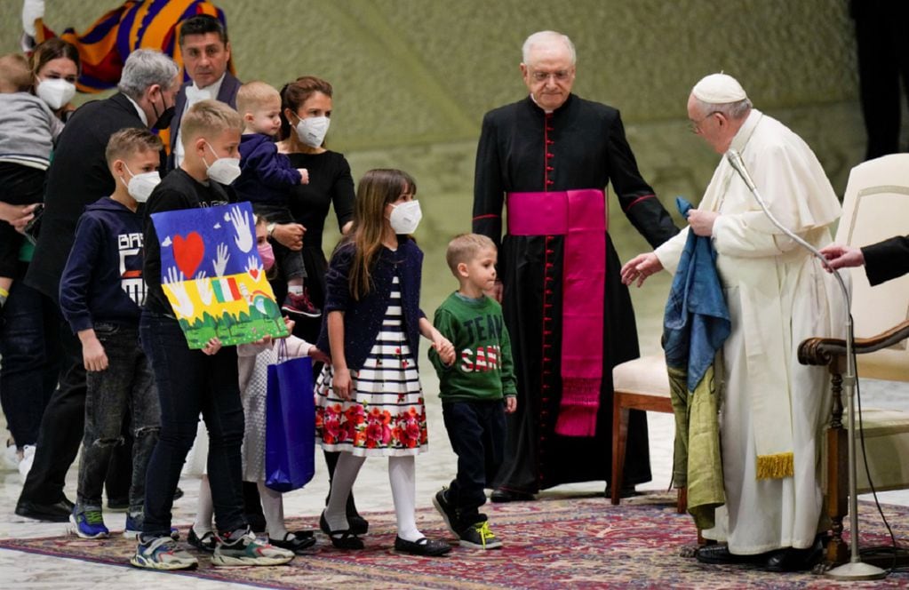 El Papa Francisco, sosteniendo una bandera que le fue traída desde Bucha, Ucrania, saluda a los niños refugiados durante su audiencia general semanal en el Aula Pablo VI, en el Vaticano, el miércoles 6 de abril de 2022. (AP)