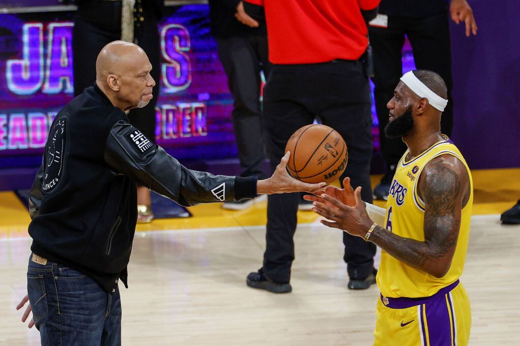 Kareem Abdul-Jabbar le da una pelota a LeBron en medio de su homenaje por convertirse en el máximo anotador histórico de la NBA. (DPA)