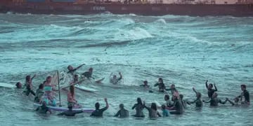 Cerca de 50, entre profesionales, famosos y amateurs, se metieron en un mar embravecido para realizar el mítico círculo y tirar flores. 