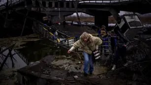 Una mujer corre mientras huye con su familia a través de un puente destruido en las afueras de Kiev, Ucrania.