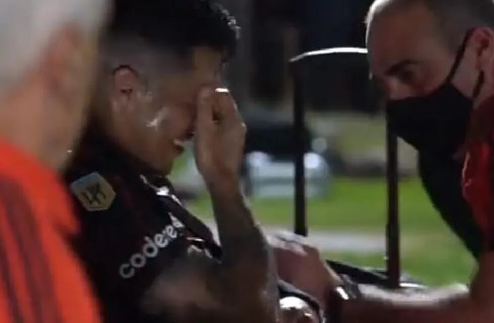 Enzo Pérez y el codo fuera de posición, tras la fuerte caída. El kinesiólogo del equipo lo atiende y trata de animarlo. /Captura de video.