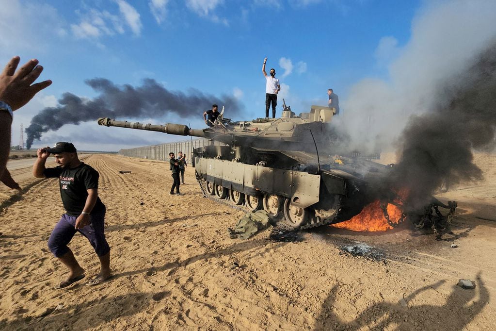 Palestinos celebran junto a un tanque israelí destruido en la valla de la Franja de Gaza al este de Khan Younis, al sur. (AP)