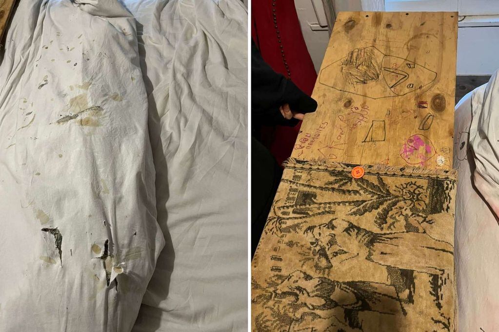 Sábanas manchadas y una tabla de madera, con dibujos y garabatos, colocada en la punta de la cama.