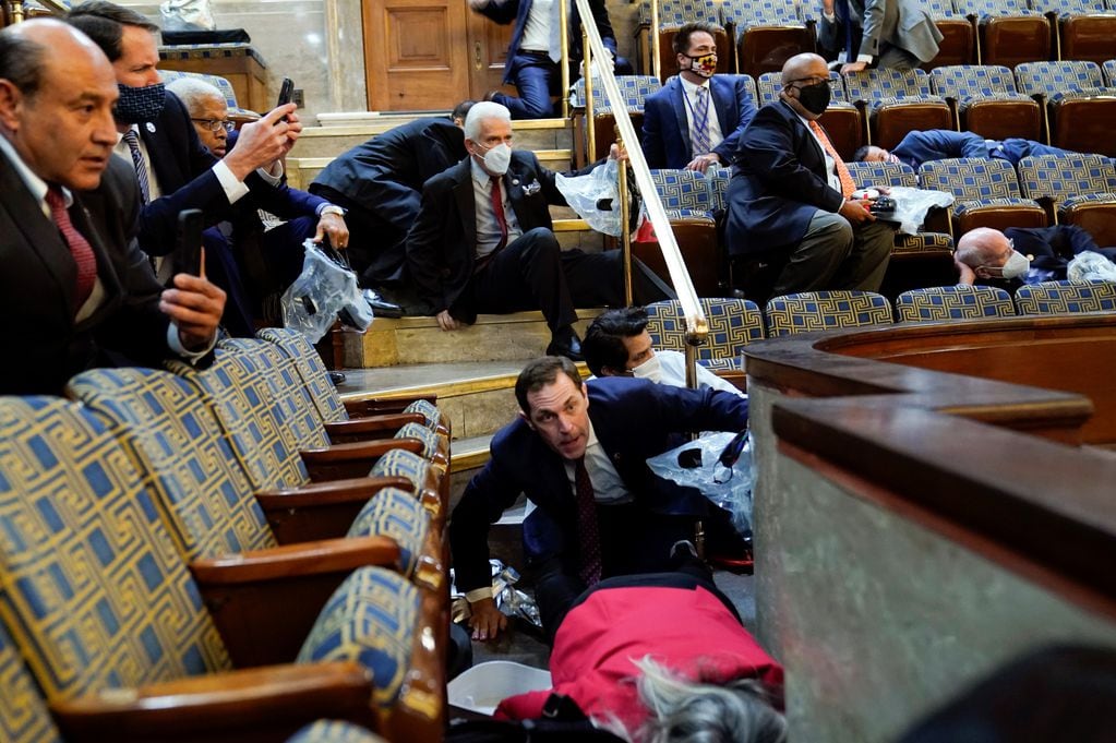 Las personas se refugian en la galería de la Cámara mientras los manifestantes intentan irrumpir en el Capitolio de los Estados Unidos. 