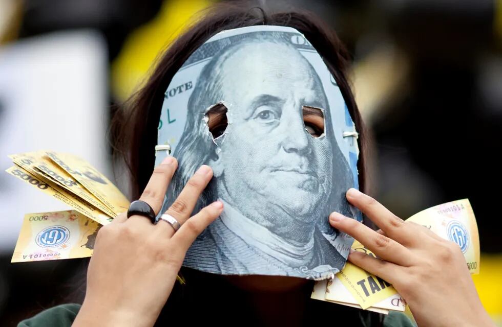 Una persona enmascarada con un detalle de un billete de 100 dólares, en protesta contra el acuerdo que firmó el gobierno de Mauricio Macri con el FMI.