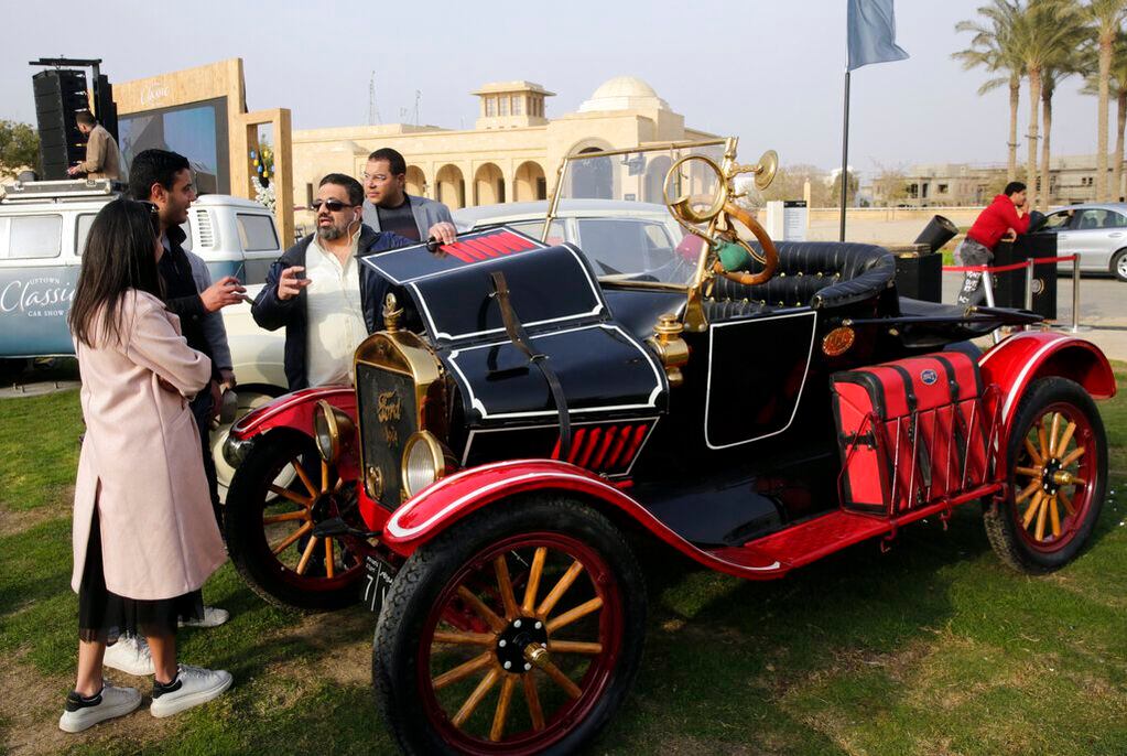 El coleccionista egipcio Mohamed Wahdan conversa con personas sobre su Ford T de 1924 durante una muestra de automóviles clásicos el sábado 19 de marzo de 2022, en El Cairo, Egipto. El vehículo perteneció alguna vez al rey Farouk de Egipto y forma parte de más de 250 coches vintage, antiguos y clásicos que Wahdan ha coleccionado durante los últimos 20 años. (AP Foto/Amr Nabil)