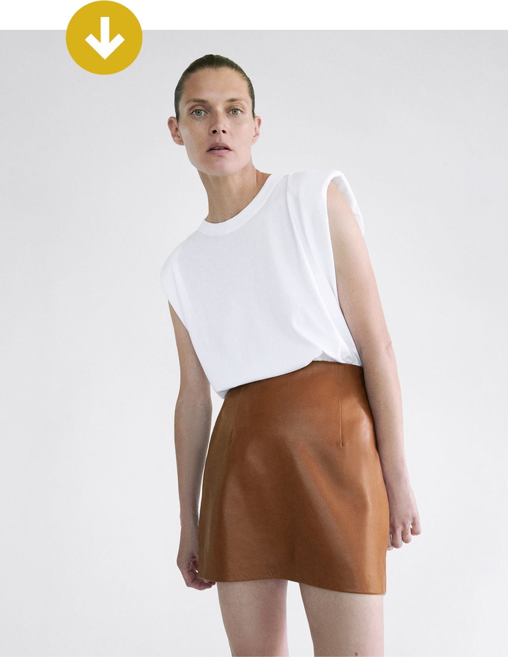Falda marrón de cuero combinada con una musculosa básica blanca.  Un conjunto clave para el día. ZARA