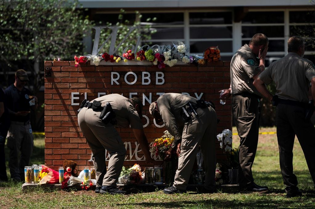 Policías colocan flores en la entrada del colegio primario de Uvalde, Texas, donde ocurrió la matanza.