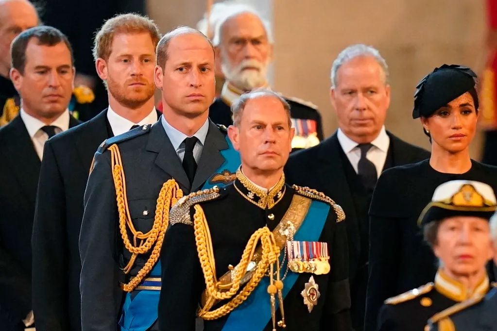 En la imagen se puede ver al Príncipe Harry vestido de traje detrás de Guillermo.