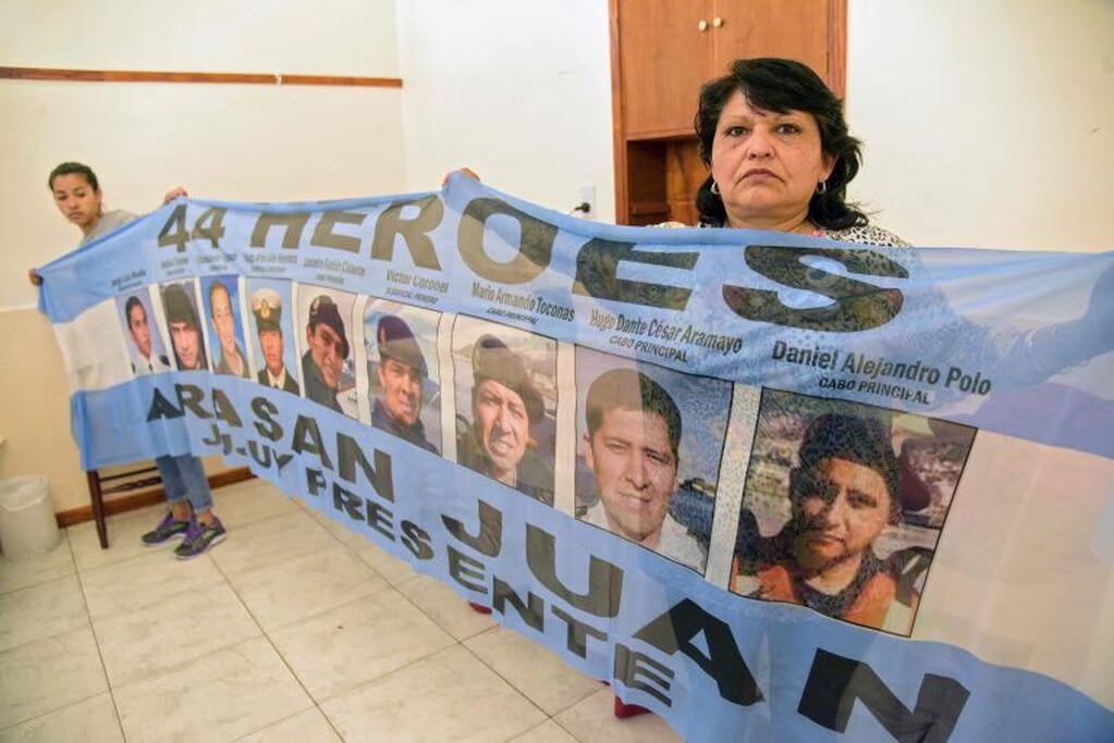 Lourdes Melián, hermana del cabo primero David Melián, y Yolanda Mendiola, madre del cabo primero Leandro Fabián Cisneros, sostienen una bandera con los retratos de los nueve tripulantes jujeños del submarino San Juan.