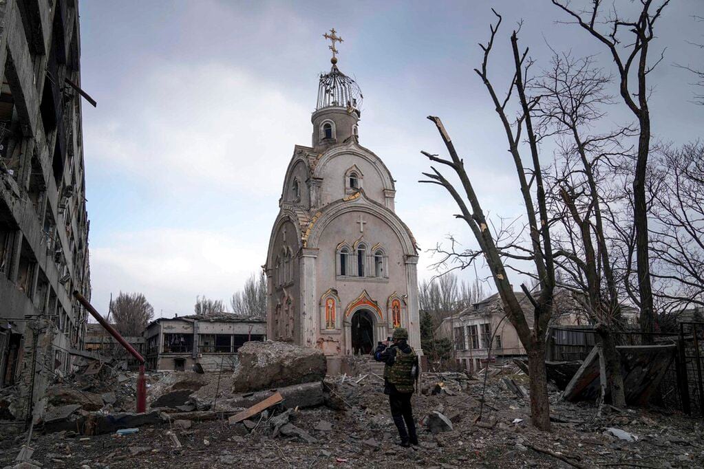 Un soldado ucraniano toma una fotografía de una iglesia dañada tras un bombardeo sobre un distrito residencial en Mariúpol, Ucrania. Foto: AP / Evgeniy Maloletka