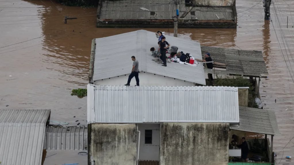 Personas esperan ayuda en el techo de su casa afectada por las inundaciones. EFE/ Isaac Fontana