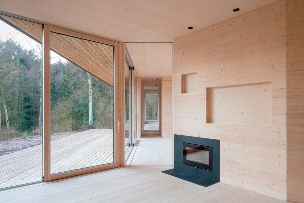 Vemos un interior de madera con puertas corredizas que hacen compartir la vida interior con el bello bosque.