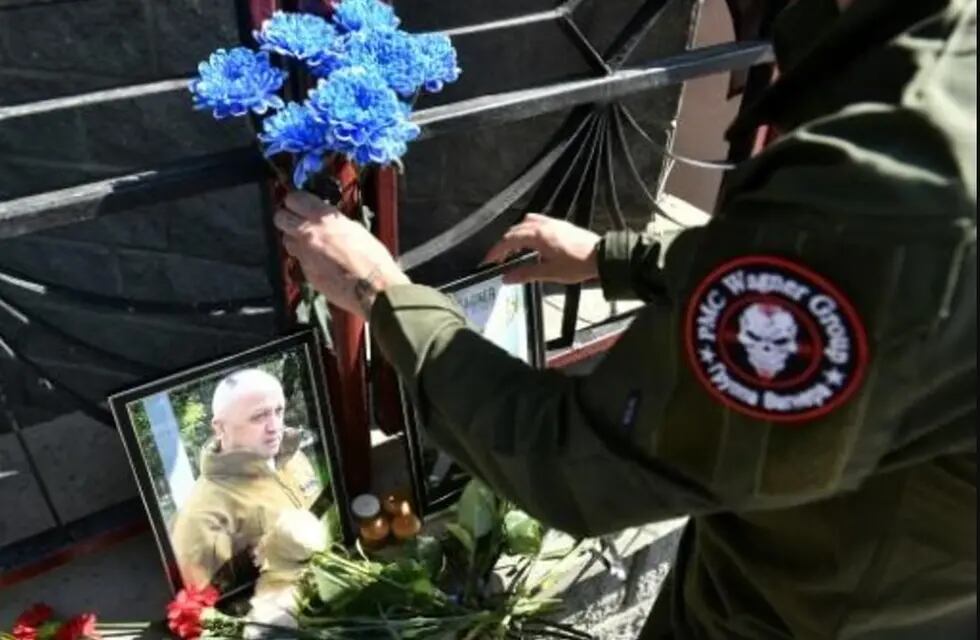 Un soldado con un parche del PMC Wagner deja flores en un altar con fotos de los líderes del grupo fallecidos.