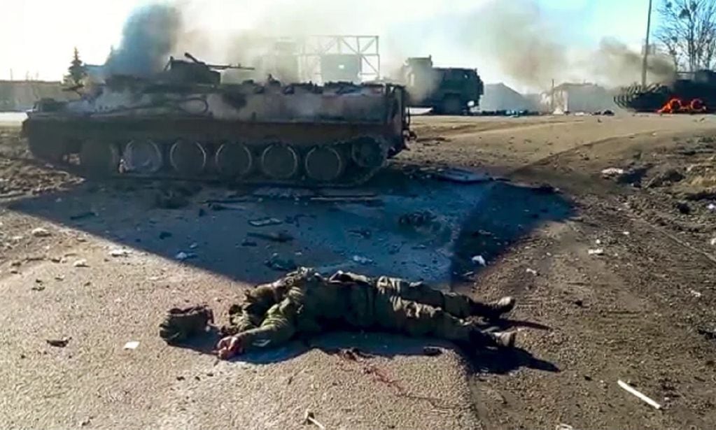 En esta foto tomada de un video publicado por el Servicio de Prensa del Departamento de Policía de Ucrania, el cuerpo de un soldado muerto yace en el suelo junto a vehículos militares destrozados (AP)