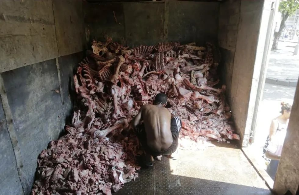 Un brasilero revolviendo carne podrida para poder comer (O Globo / Domingos Peixoto)
