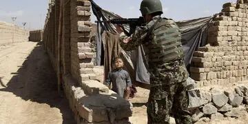 Demasiada guerra. Un soldado afgano apunta con su arma en las afueras de Kabul; el niño es testigo (AP).