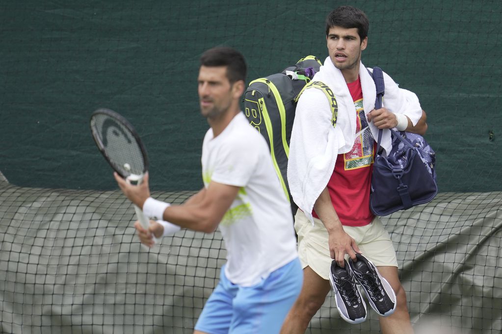 Novak Djokovic y Carlos Alcaraz durante un entrenamiento previo a Wimbledon. El serbio y el español jugarán la gran final. (AP Foto/Kin Cheung)