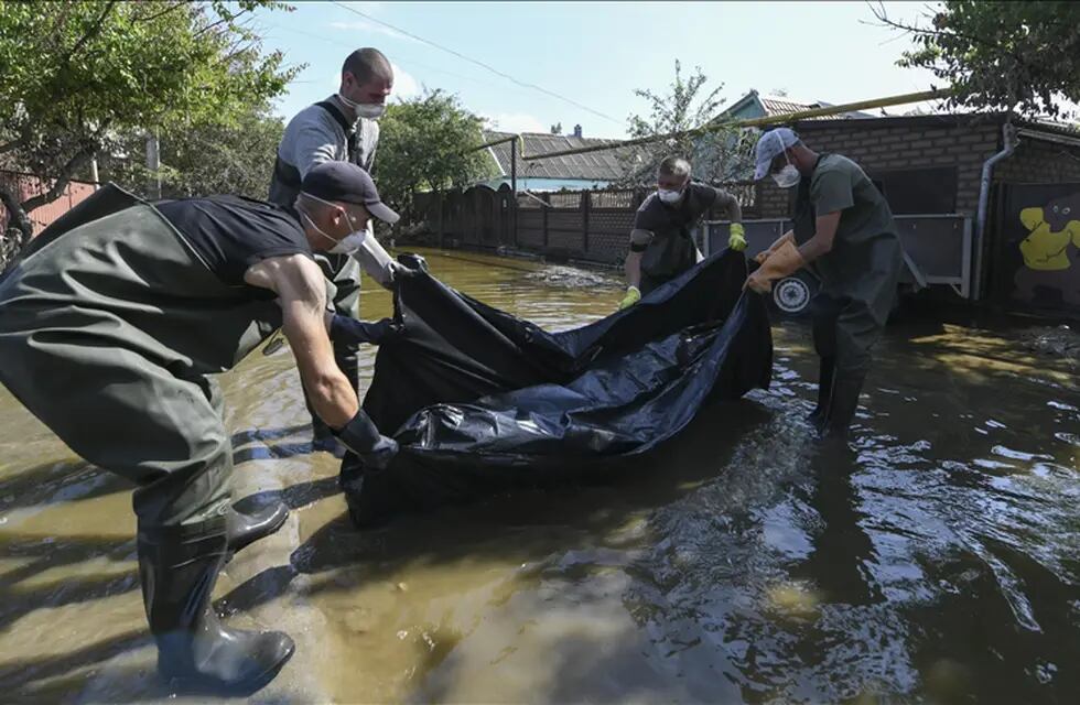 Equipos de rescate rusos trasladan un cadáver encontrado en una casa inundada luego de la destrucción de la represa de Nova Kajovka, en el óblast de Jersón.