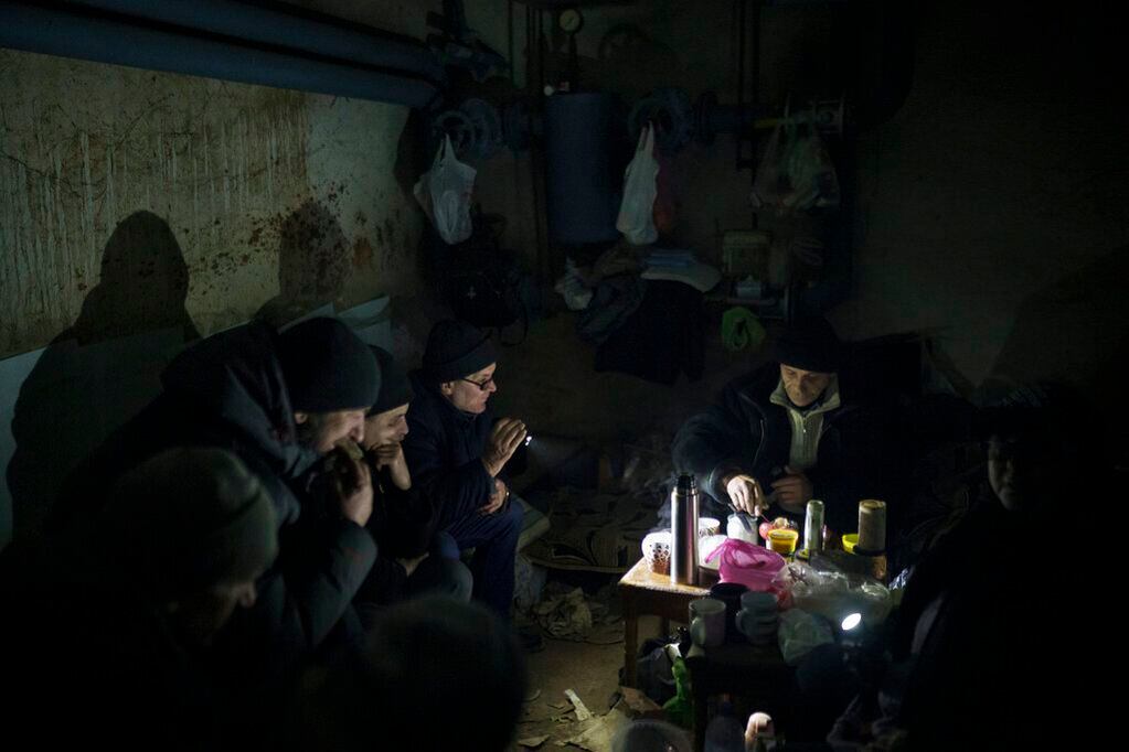 Vecinos preparando té mientra se sientan en un sótano utilizado como refugio antibombas. Foto: AP / Felipe Dana