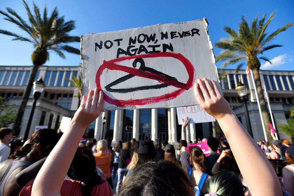 Una manifestante sostiene un cartel que dice "Ni ahora ni nunca más" frente al juzgado del condado de Duval, Florida. (AP)