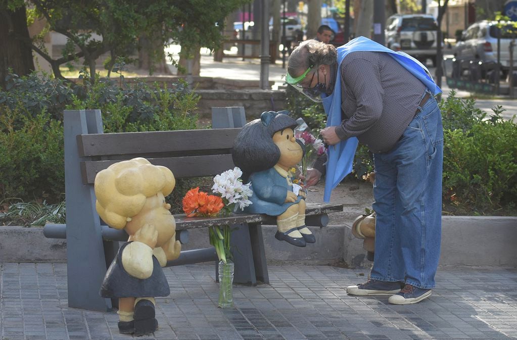 Un hombre pone flores en la escultura de Mafalda para homenajear a Quino quien falleció a sus 88 años.